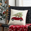 Housse de coussin de Noël écrue avec une voiture rouge qui transporte un sapin