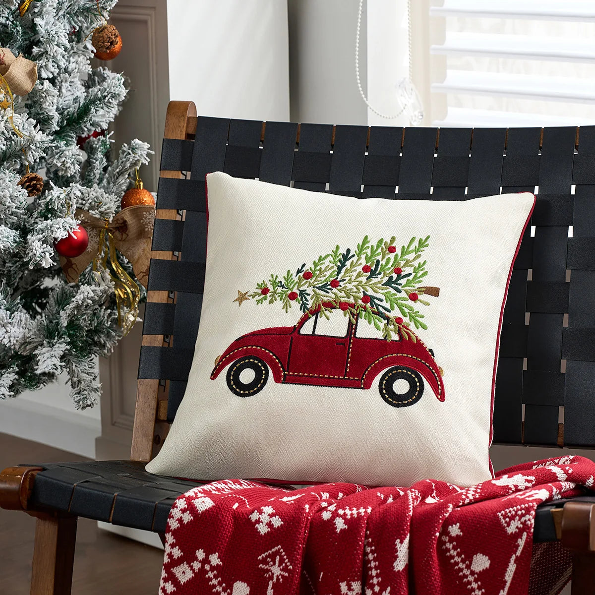 Housse de coussin de Noël écrue avec une voiture rouge qui transporte un sapin