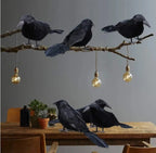 La Volée de Corbeaux posée sur une branche et une table
