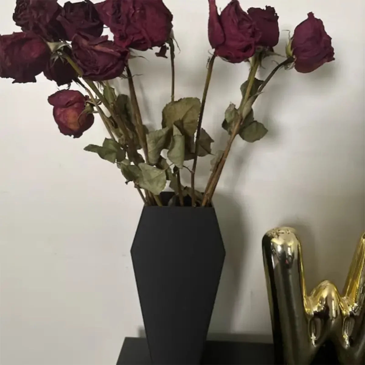 Vase cercueil avec une rose rouge sur une étagère